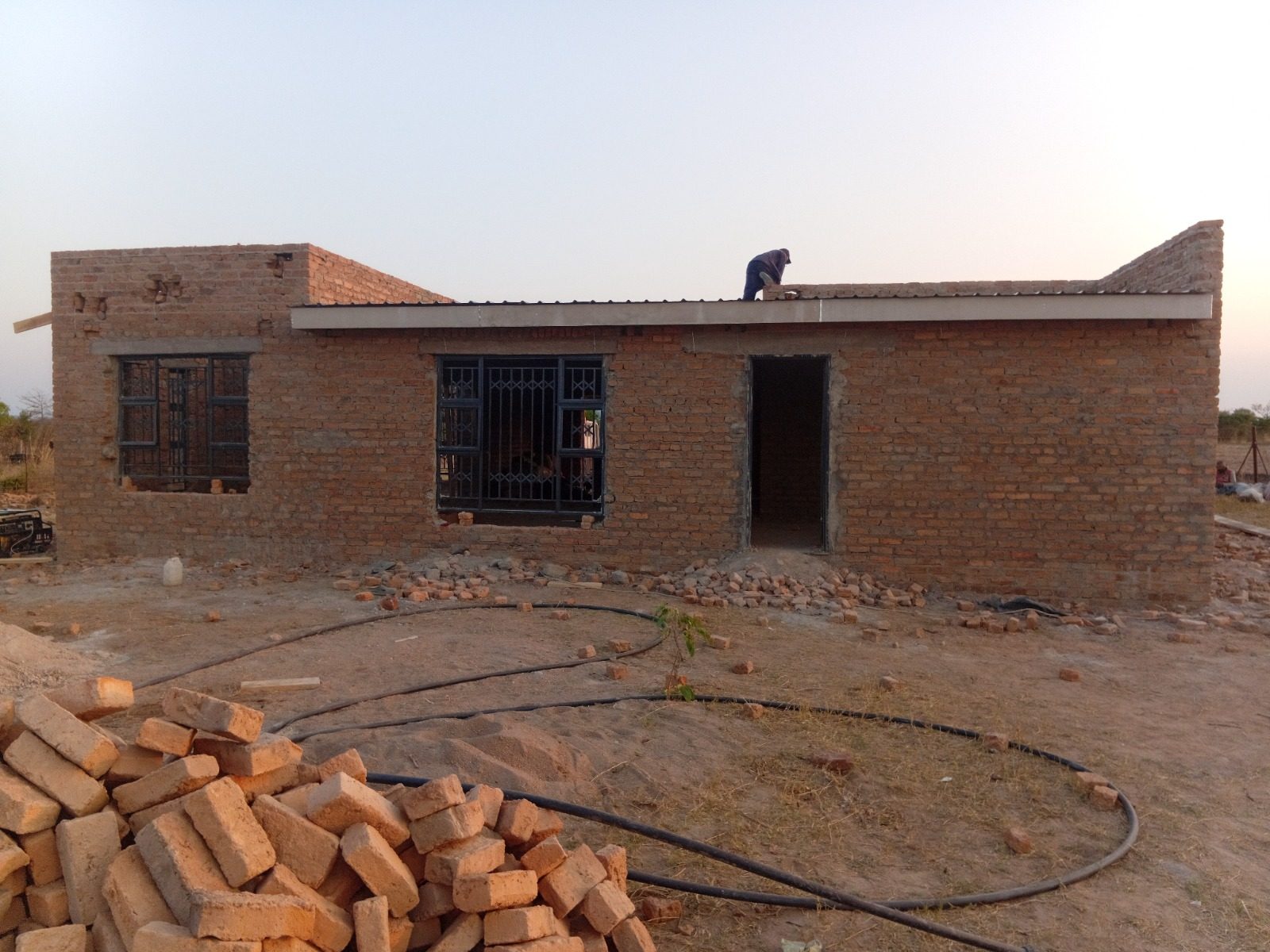 Brick cottage with a worker fitting the roof sheet